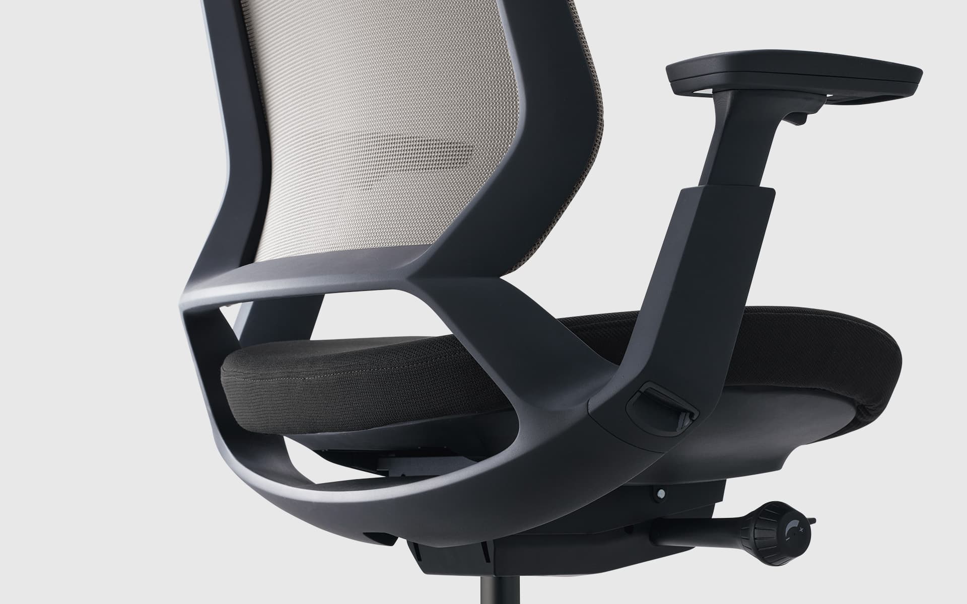 Enlarged partial angled back view of an Okamura Abilis office chair with beige mesh backrest, black upholstery and dark grey frame.